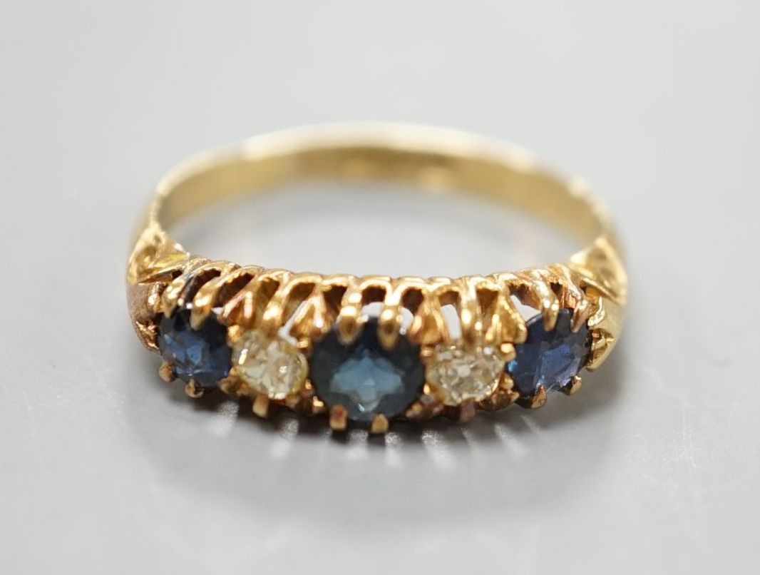 A George V 18ct gold, three stone sapphire and two diamond set half hoop ring, size M, gross 3.1 grams.